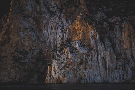 Dramatic cliff illuminated by sunlight, showcasing fascinating rock formations and textures.