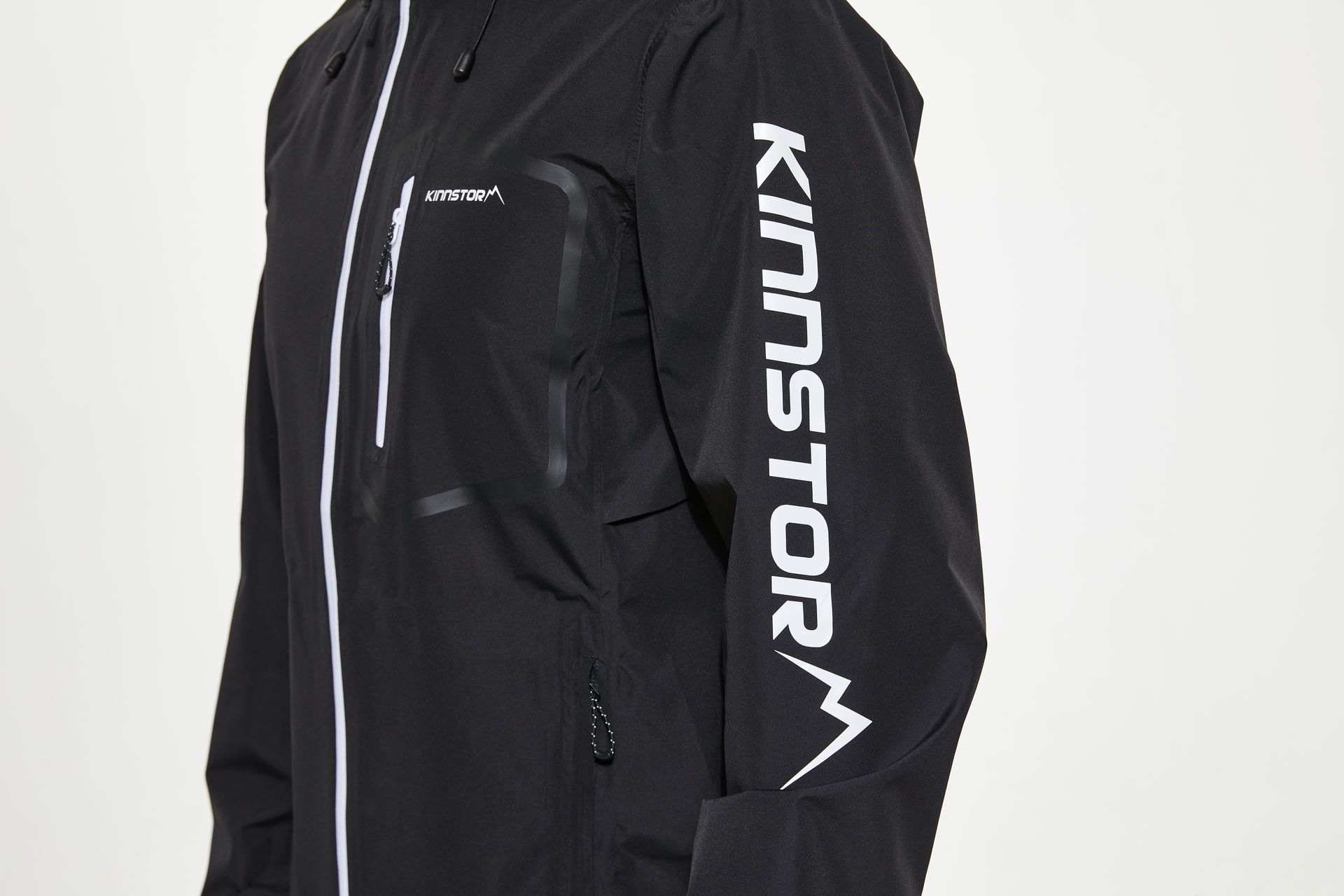 Close-up shot of a black jacket featuring KINNSTORM branding on the sleeve for fashion and lifestyle use.