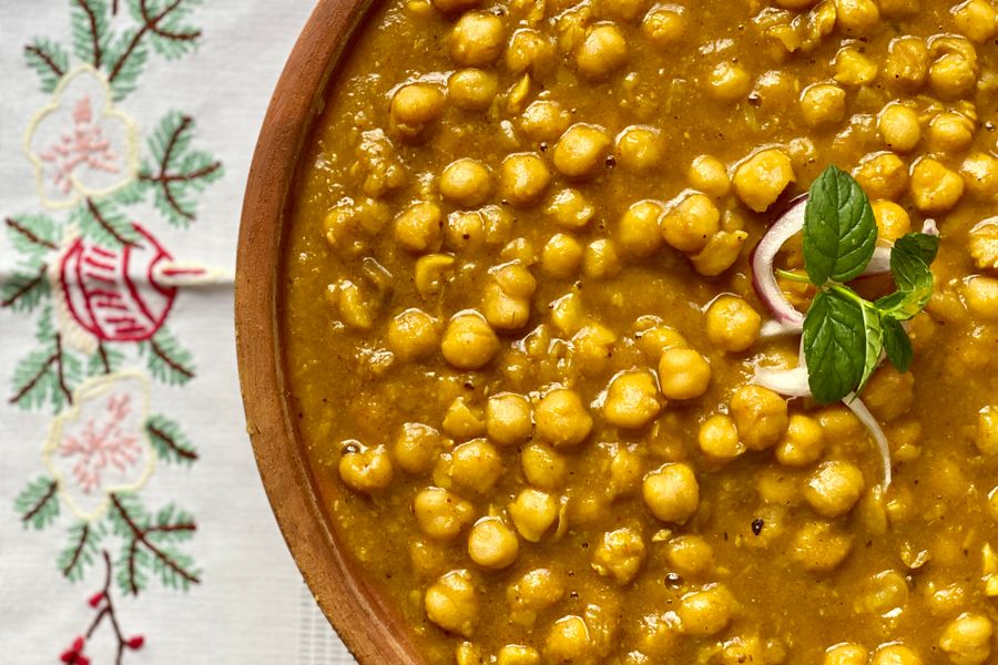 Delicious close-up of Chana Masala, a flavorful Indian dish garnished with mint and onion.