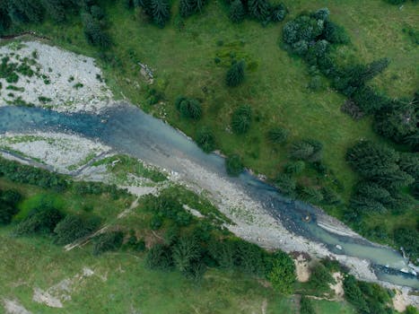 A drone captures a serene river flowing through lush greenery in Bukovel, Ukraine.