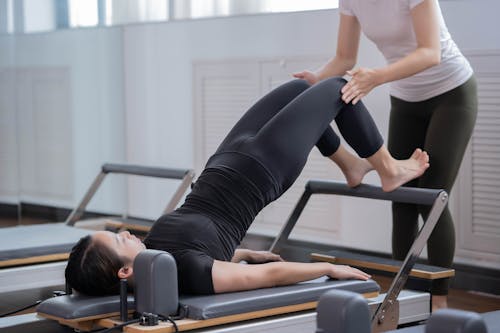 Free Fitness Instructor Assisting Woman Doing Pilates Stock Photo