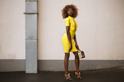 Woman in Yellow Knitted Dress Holding Beige Handbag