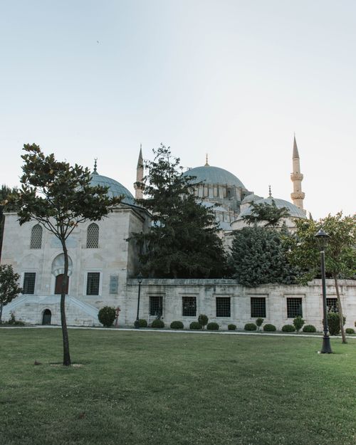Free A serene view of a historic mosque with a lush garden, showcasing architectural beauty under a clear sky. Stock Photo