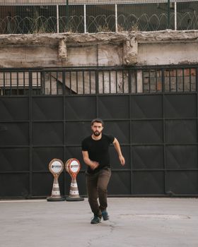 A man runs outdoors near an industrial gate, showcasing urban fitness and determination.