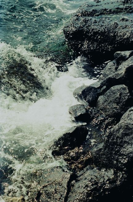 Powerful ocean waves crashing against dark, rocky coast, creating dramatic splashes and foam.