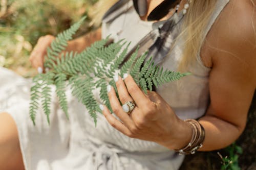A Woman Holding a Frond of Fern Leaves
