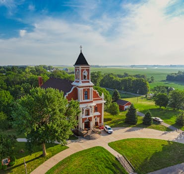 Aerial view of a historic church in the rural landscape of New Trier, MN, showcasing lush greenery.