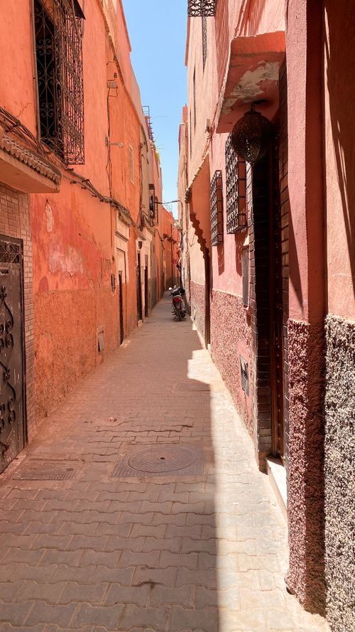 Free Exploration of a narrow alley with colorful walls and parked motorcycle on a sunny day. Stock Photo