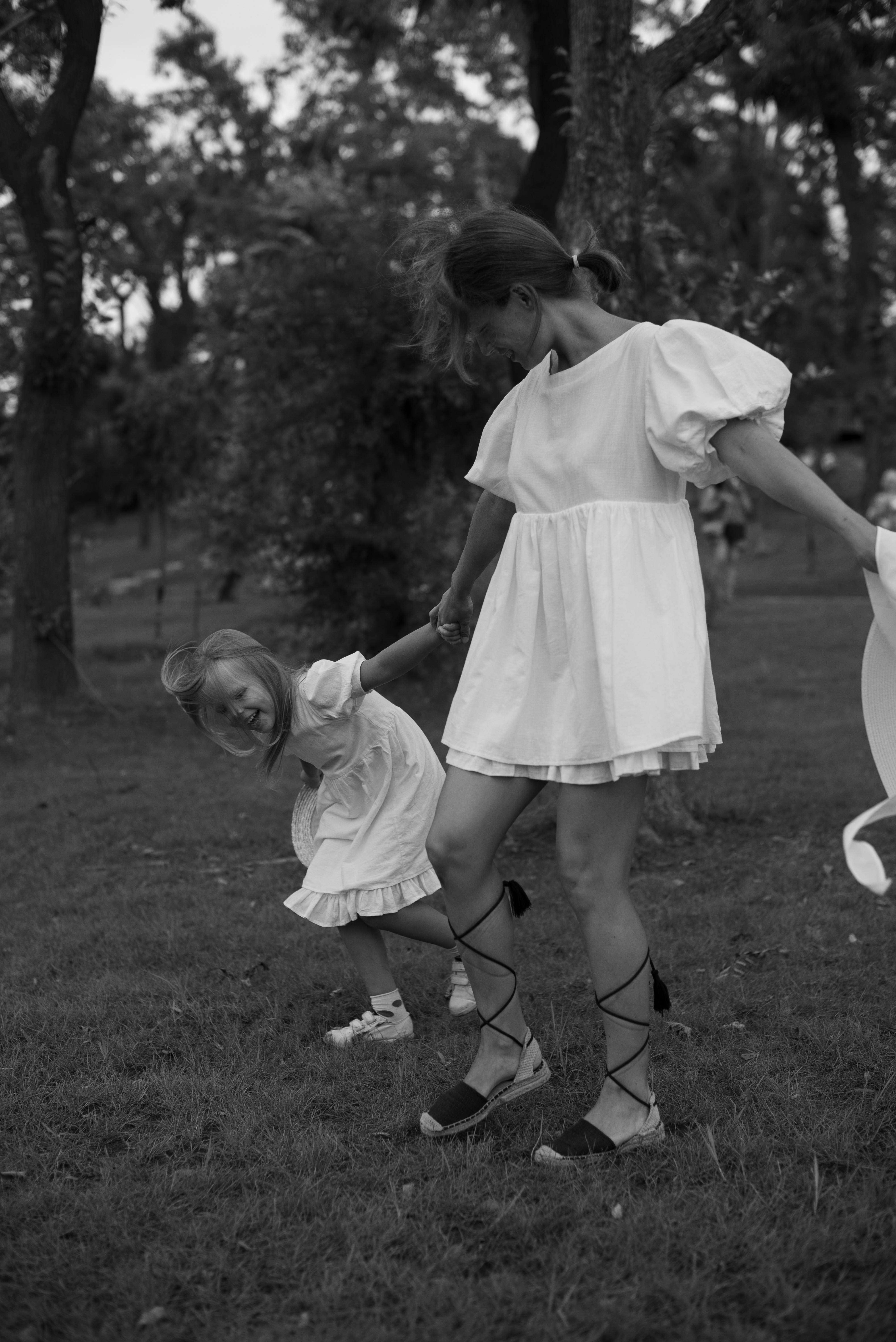 Black and white photo of a cheerful mother and daughter playing outdoors, capturing joy and togetherness.