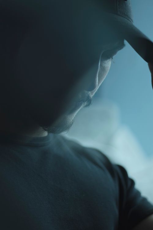 Free Moody portrait of a man in a baseball hat, captured with selective focus and defocused background. Stock Photo