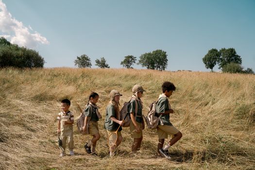 Group of kids exploring a sunny field on an outdoor adventure at summer camp.