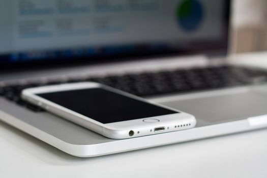 A close-up image of a smartphone resting on a laptop keyboard showcasing modern technology devices.