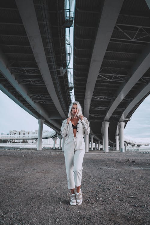Woman in White Outfit Standing under a Bridge 