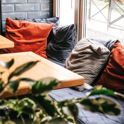 A window seat piled with ochre cushions and woven throws, photo by Alexandra Kollstrem on Pexels
