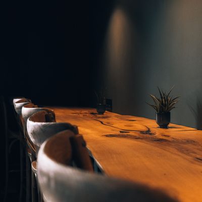 Long wooden communal table in a dim dining room — Alexandra Kollstrem on Pexels