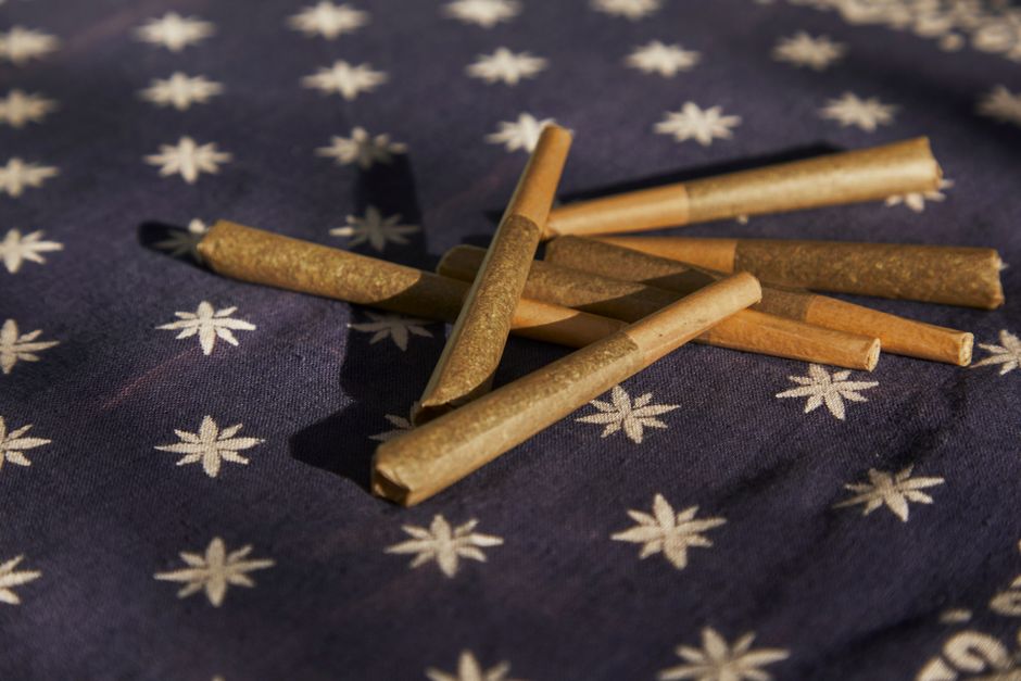 A premium kief-coated infused pre-roll with a clean glass tip showing the layers of concentrates A premium kief-coated infused pre-roll with a clean glass tip showing the layers of concentrates