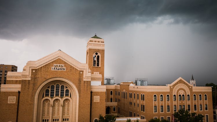 A Brown First Baptist Church Under Gray Sky