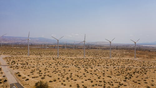 White Windmills on Brown Field Under Blue Sky