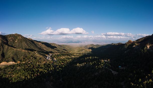 Breathtaking panoramic view of lush green valley surrounded by towering mountains under a clear blue sky.