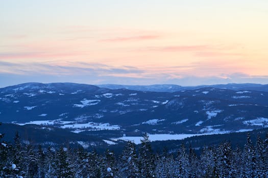 Scenic view of snowy mountains at dawn with vibrant skies, capturing winter's beauty.