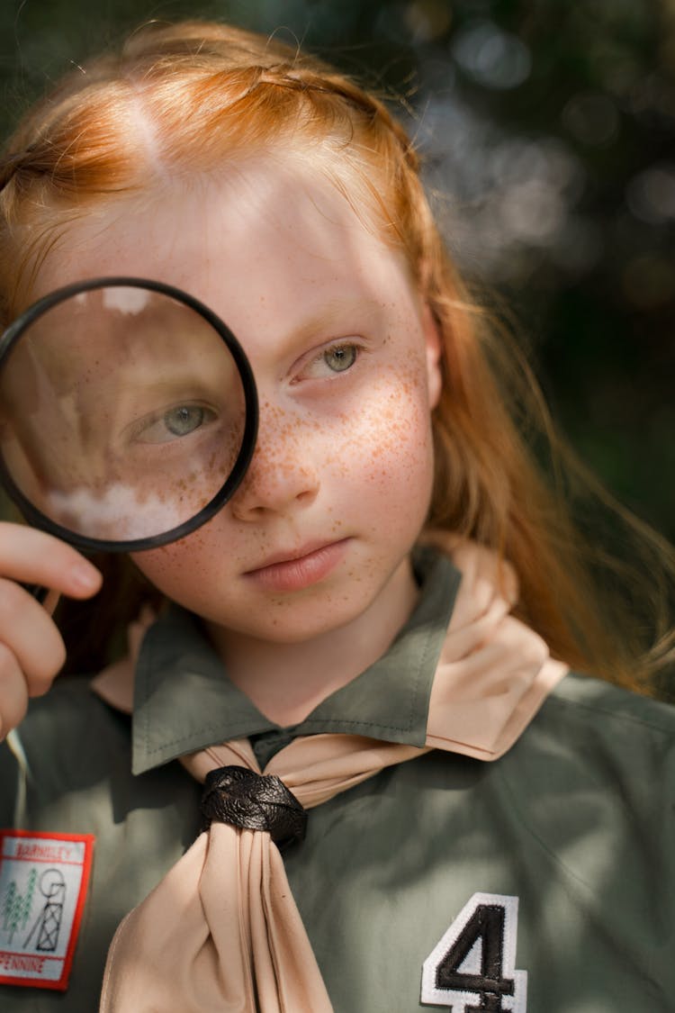 A Girl Scout Holding A Magnifying Glass 