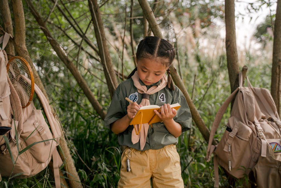 A young girl scout takes notes during a summer camp in the woods.