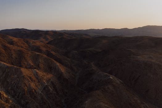 A stunning aerial view of a desert mountain range during dusk, showcasing the raw beauty of nature.