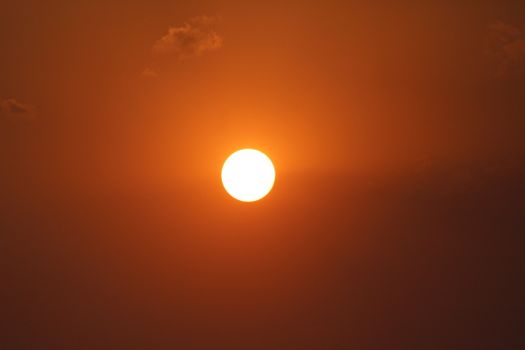 A stunning sunset with a vibrant orange sky and glowing sun creates a warm, serene atmosphere.