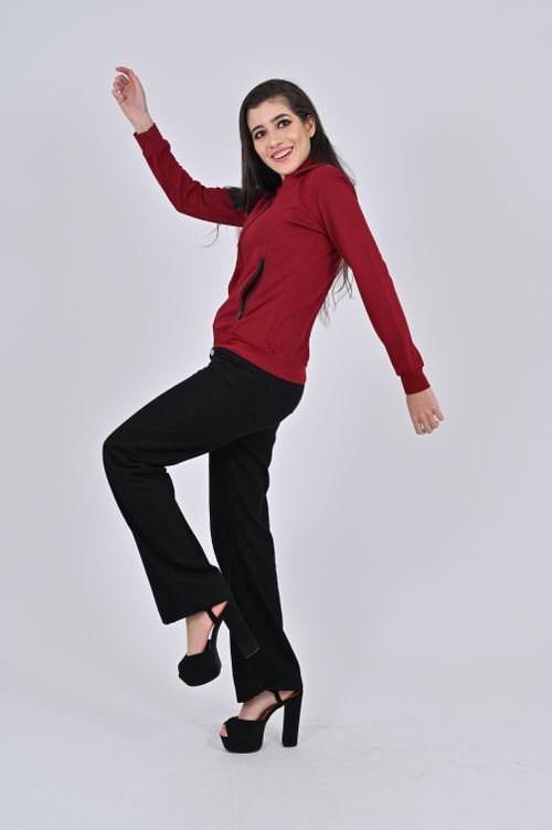 Free A young woman in a red top and black pants playfully poses against a neutral background. Stock Photo