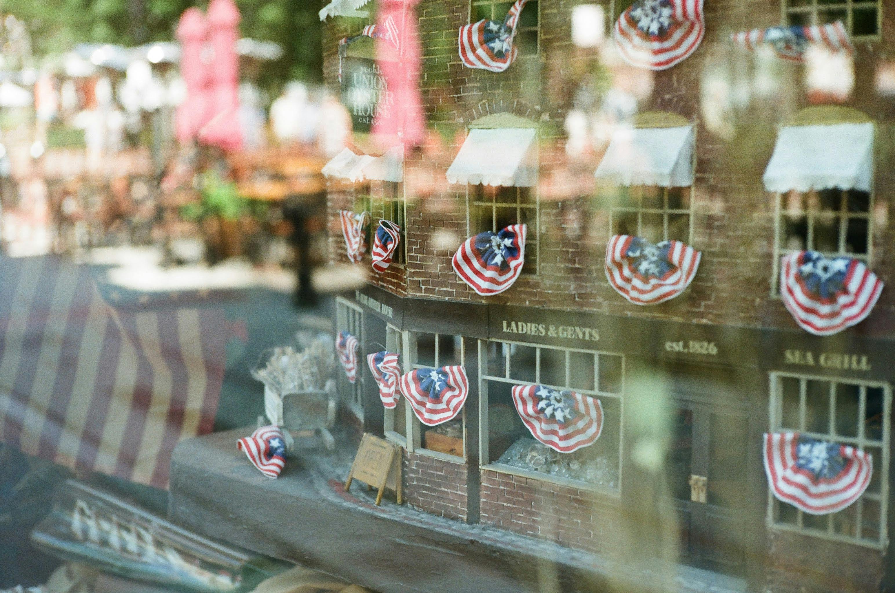 A charming Boston shop window display adorned with patriotic American flags and festive decor.