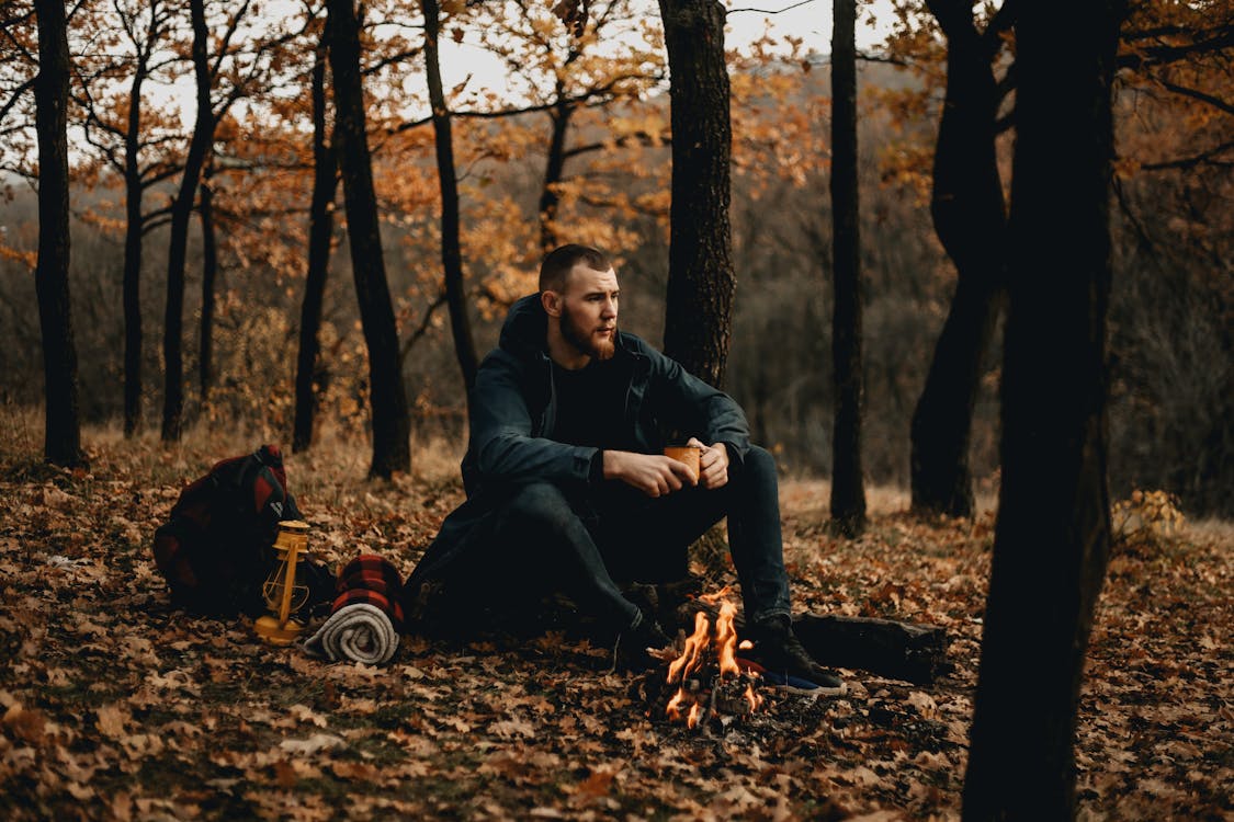 An Adventurer Holding a Cup and Sitting by the Campfire · Free Stock Photo
