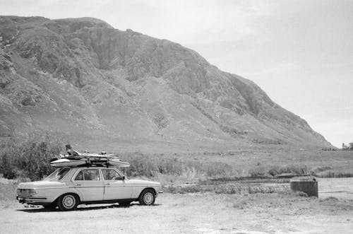 Grayscale Photo of a Classic Car with Surfboards