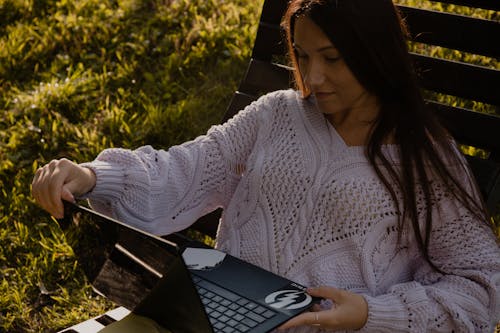 Woman in White Knit Sweater Using Black Laptop Computer