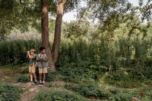 Boys in Green and Brown Uniform Standing beside Brown Trees