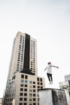 一名男子在城市屋顶优雅跃下，在天际线间展示跑酷技巧