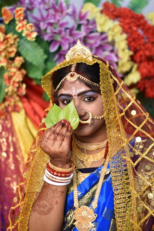 A Woman in a Traditional Indian Outfit Covering her Face with Leaves