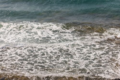 Free Vibrant ocean waves breaking on a rocky shoreline, captured from a high viewpoint. Stock Photo