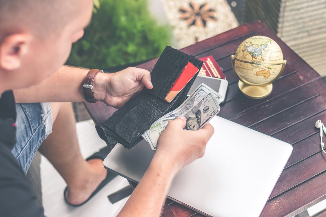 Man Holding U.s Dollar Banknotes and Black Leather Bi-fold Wallet