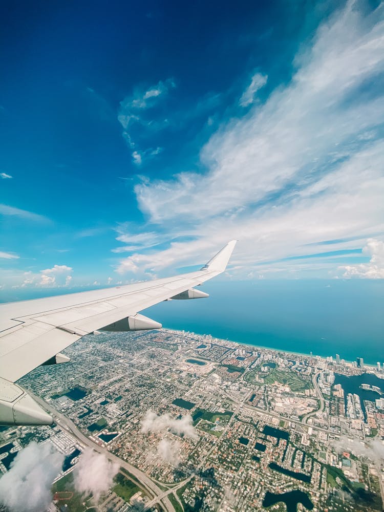 Aerial Shot Of Airplane Wing, City And Sea Landscape