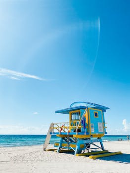 Colorful lifeguard tower on Miami's sandy beach under a clear blue sky.