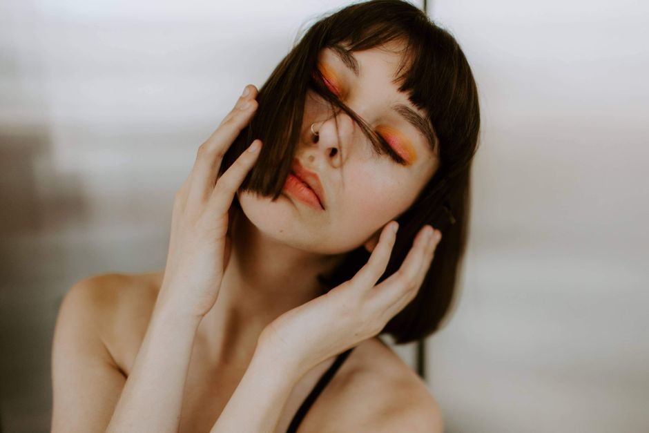 A striking portrait featuring a woman with bold makeup and a serene expression in an artistic pose.