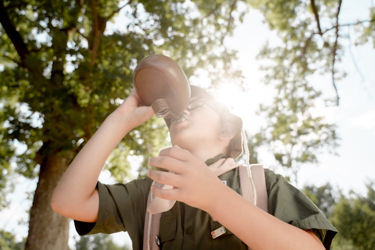 A Boy Scout Drinking From A Flask