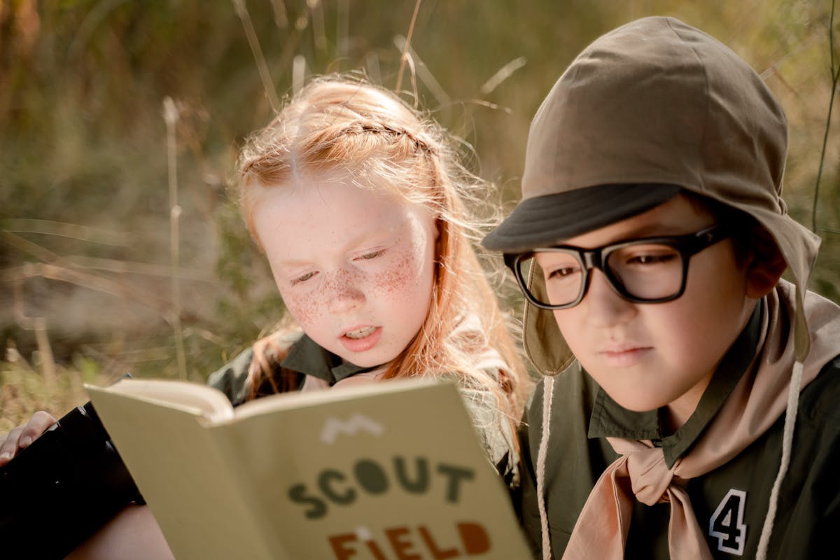 Two scouts reading together outdoors during an activity