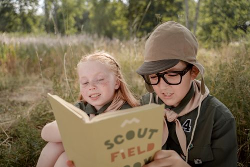 Free Two young scouts reading a field book together outside surrounded by nature. Stock Photo