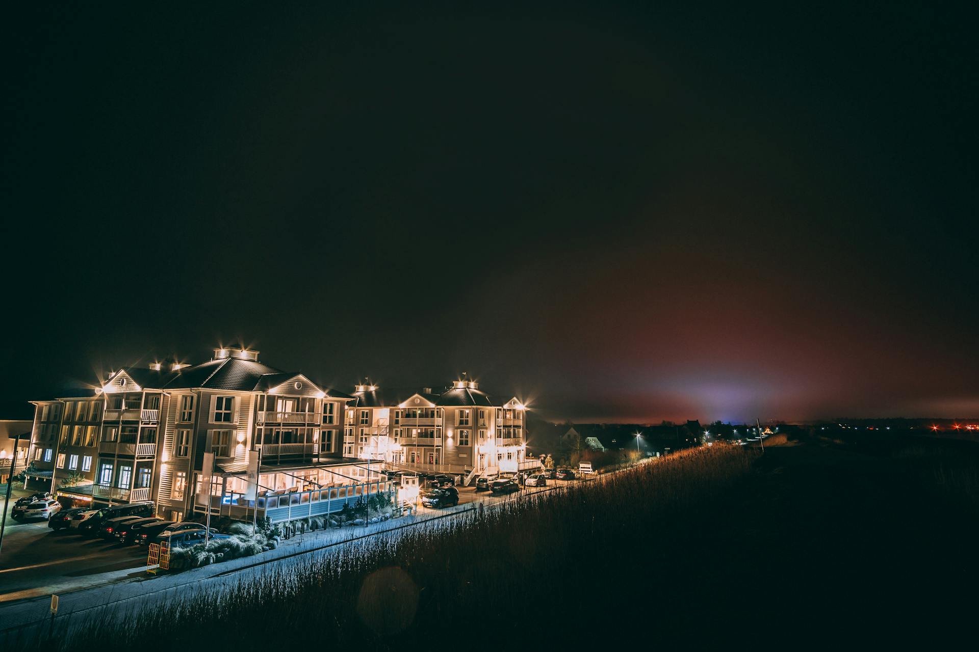 A beautifully illuminated hotel building at night with city lights reflecting on a calm river.