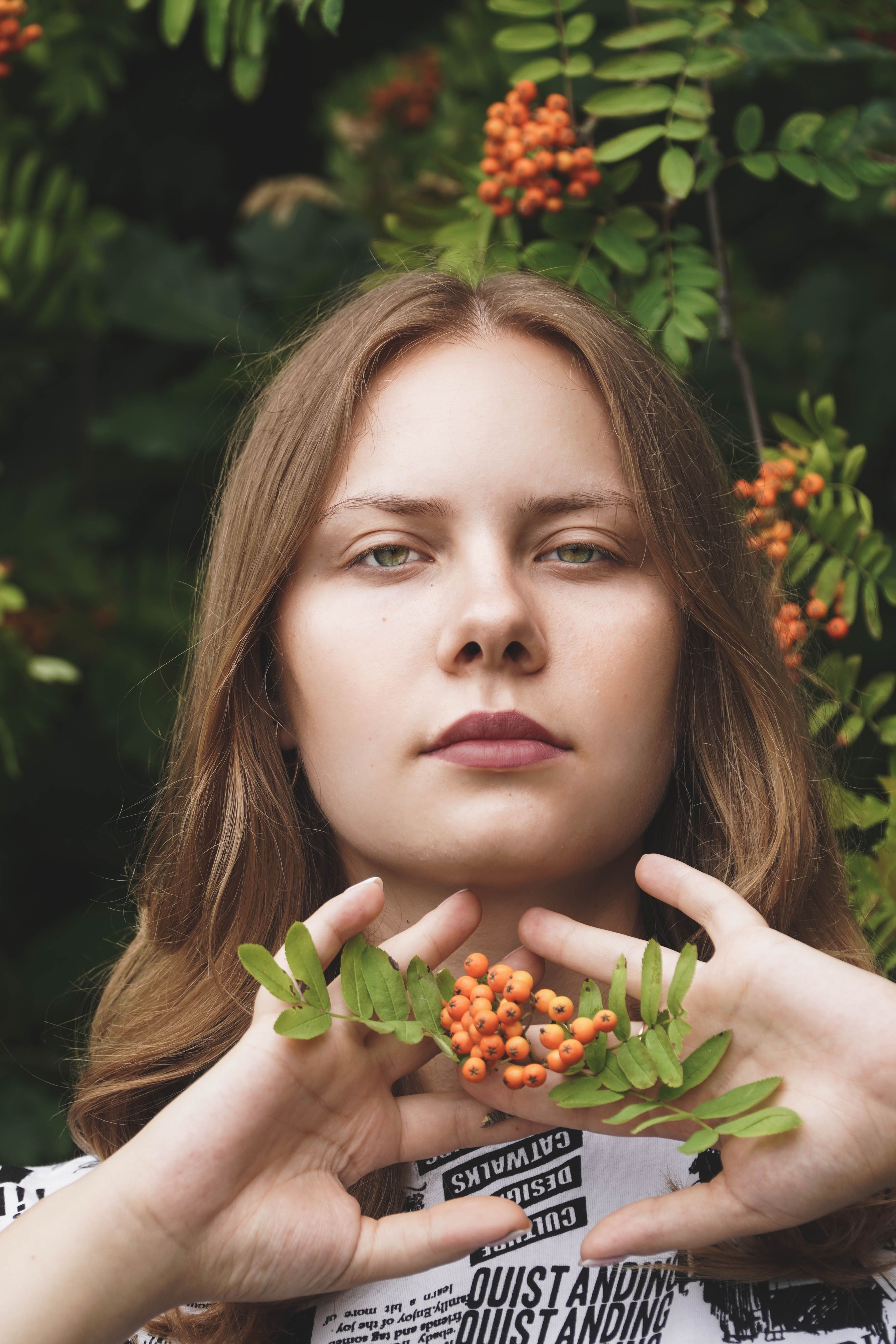 A captivating portrait of a woman holding rowan berries in a lush outdoors setting.