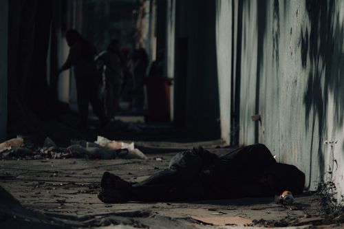 Free A contemplative urban street scene with a person lying down, reflecting loneliness and isolation. Stock Photo