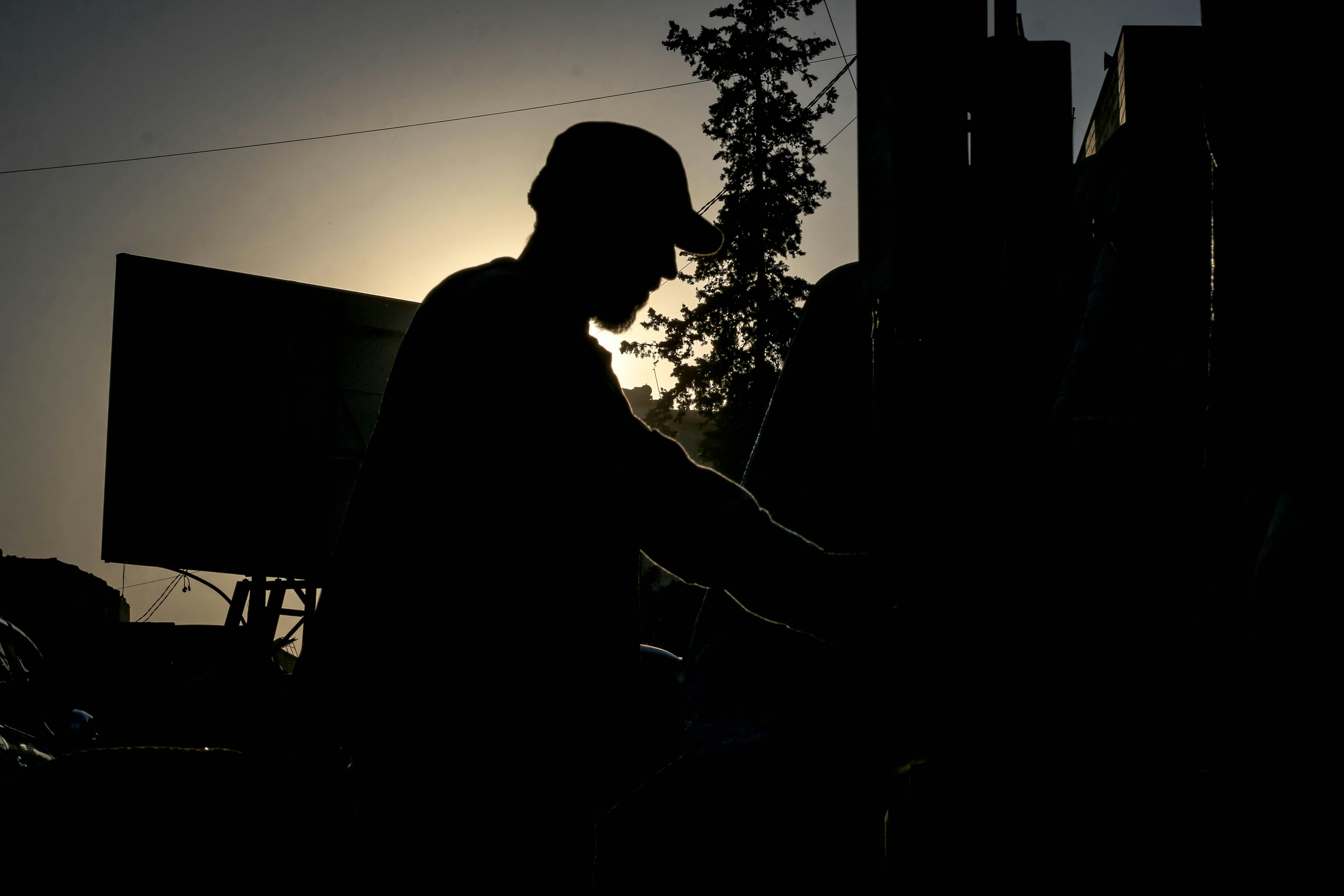 Silhouette of a man in a hat during sunset in Idlib, Syria, capturing a serene and dramatic scene.