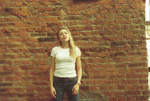 Kostenloses Stock Foto zu backsteinmauer, blondes haar, denim jeans