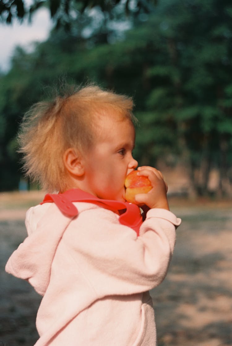 A Kid Biting A Fruit 